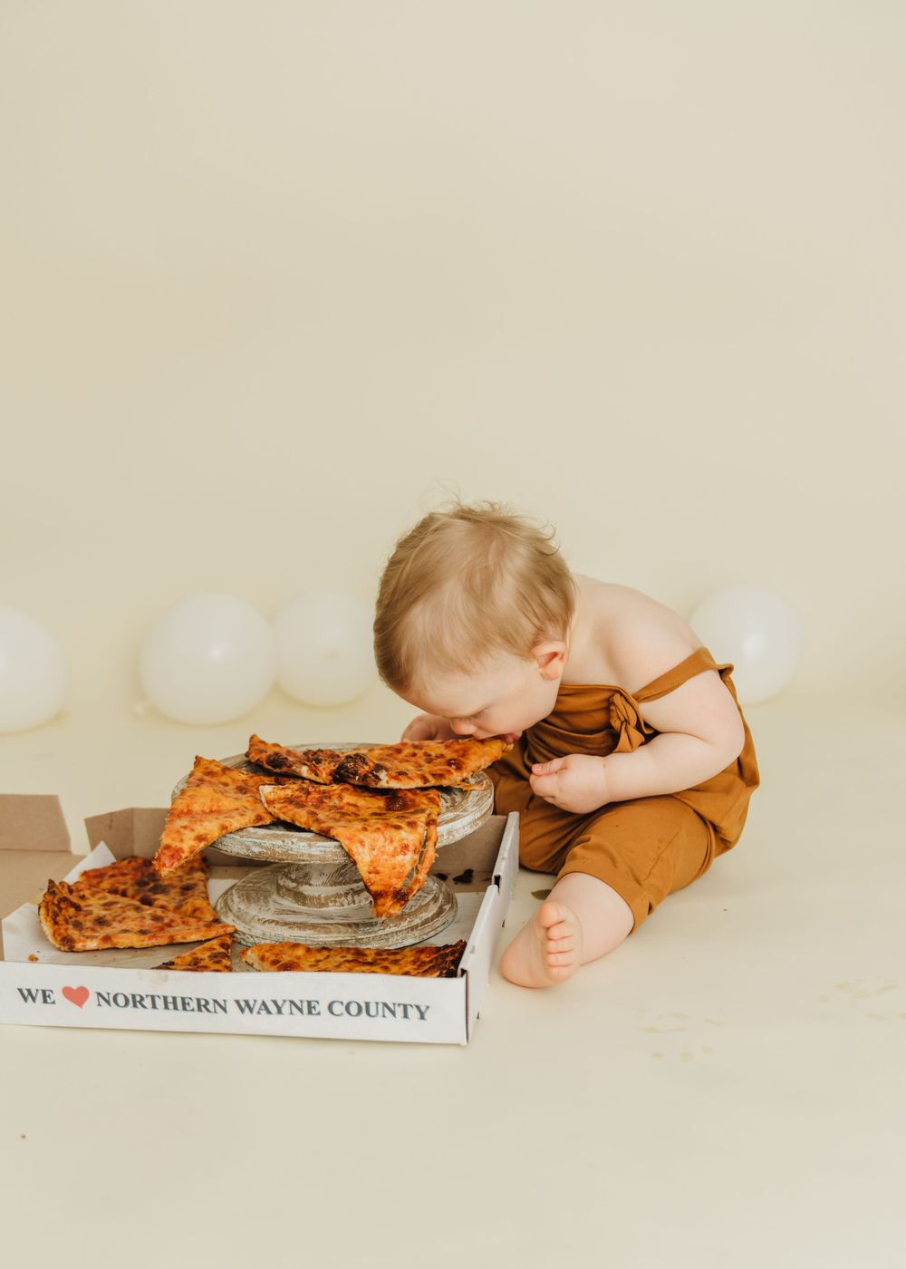 Creative pizza-themed baby photoshoot with delivery box prop.
