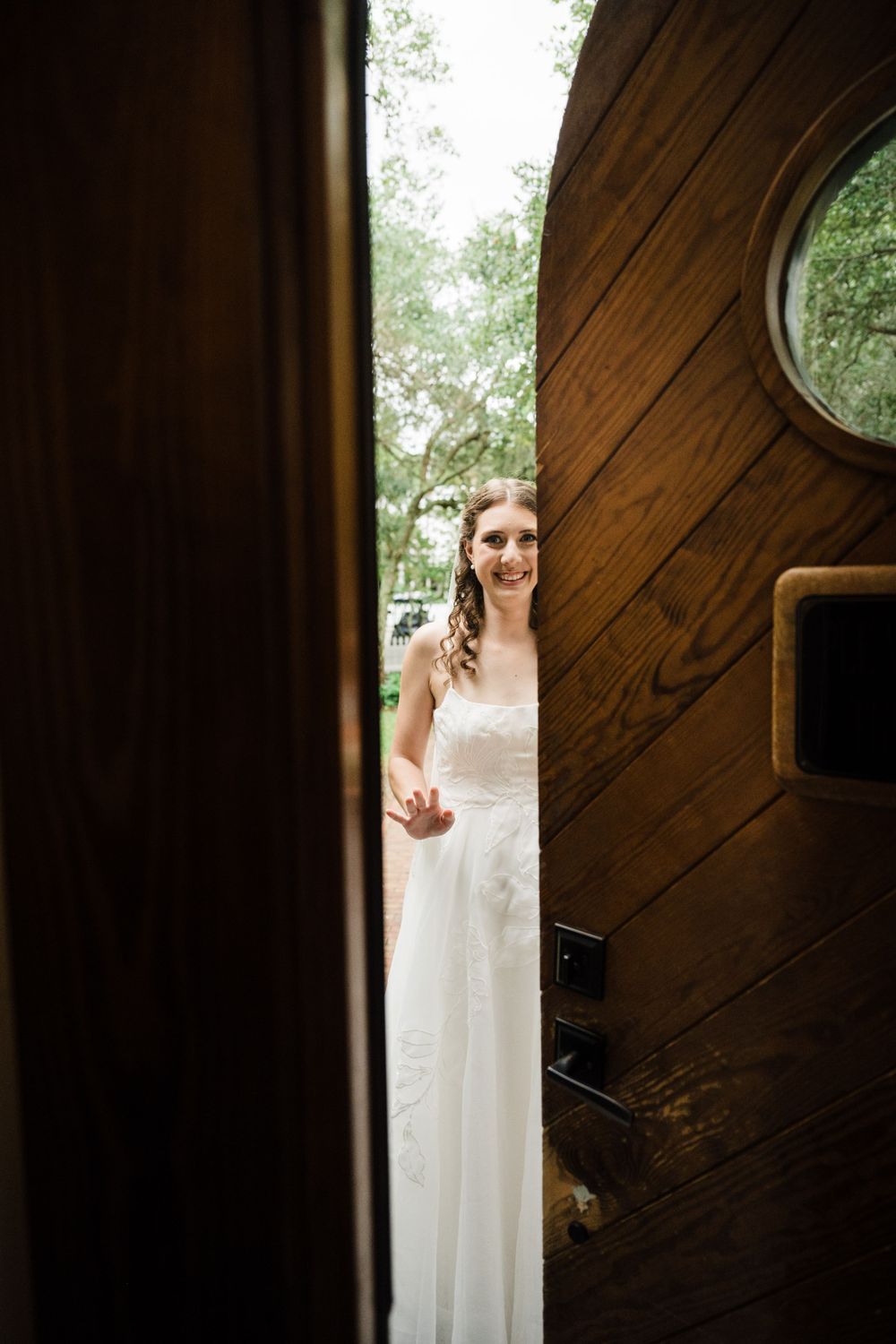 View through a doorway showing a white wedding dress against dark wood paneling with a circular window visible.