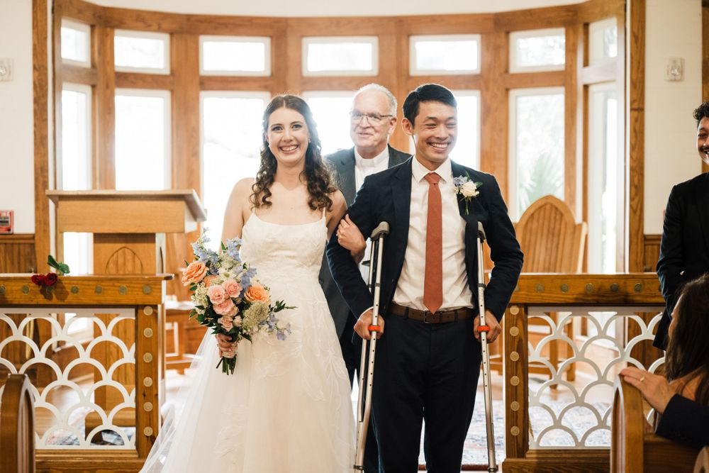 Joyful wedding celebration inside a bright chapel with large bay windows and wooden details.