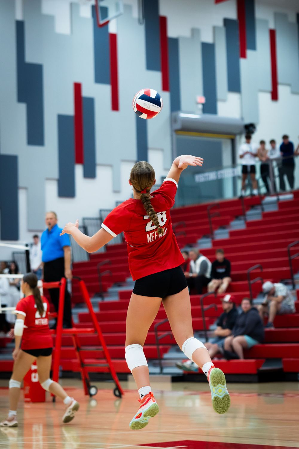 Volleyball player serving the ball during match.