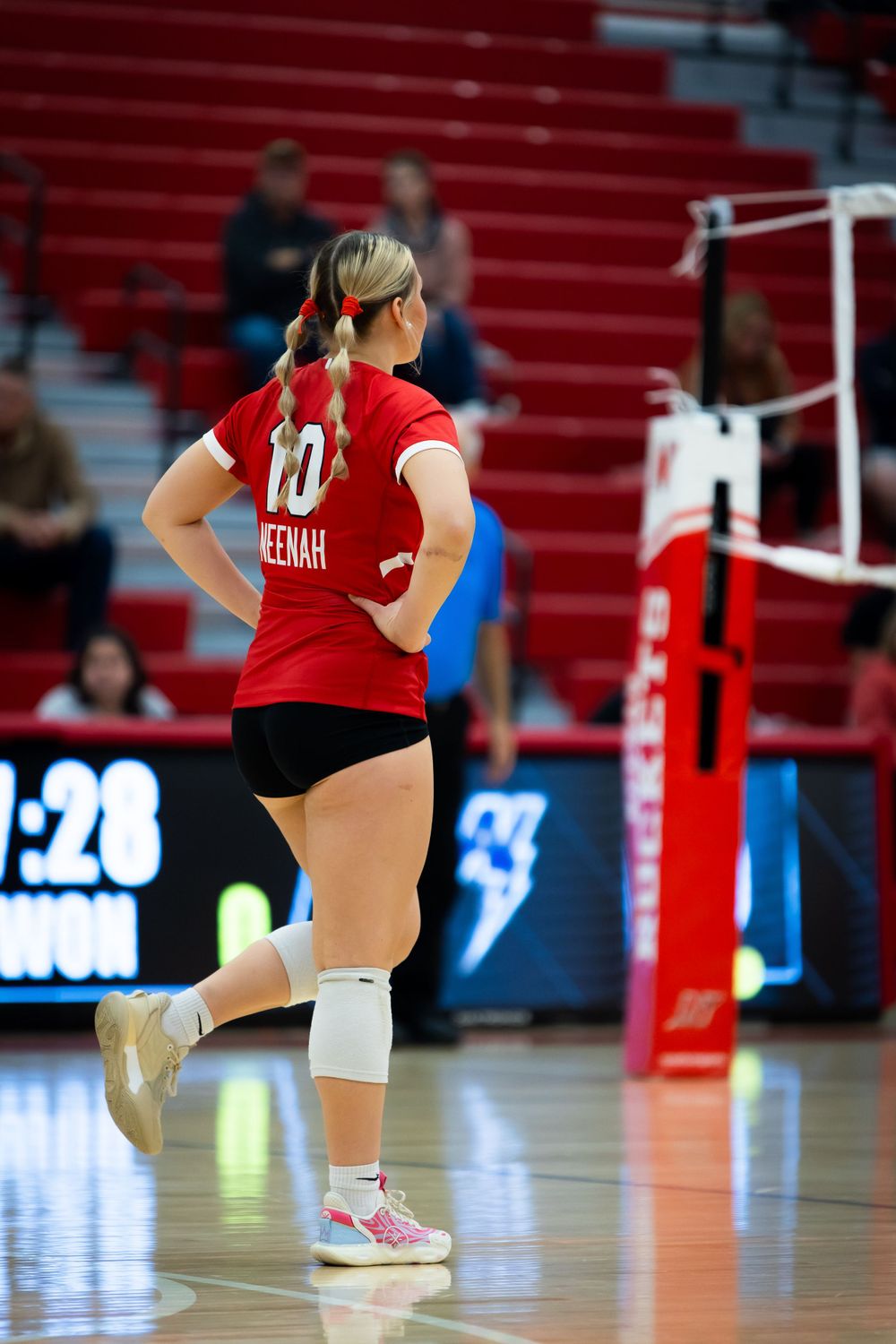 Volleyball player in red Neenah jersey stands ready on court.