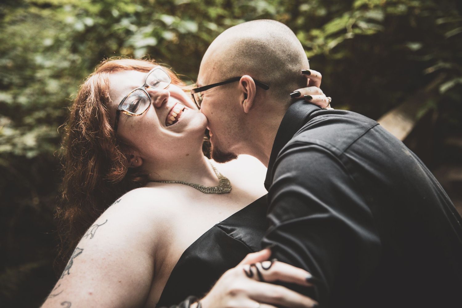 Joyful couple sharing candid laughter together on rocky cliff in black and white.