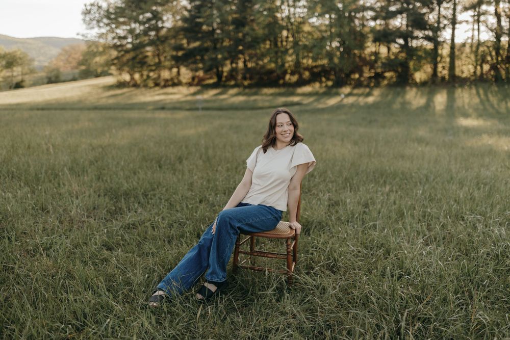 Full length portrait on antique chair in serene meadow setting. Virginia graduation/senior session.