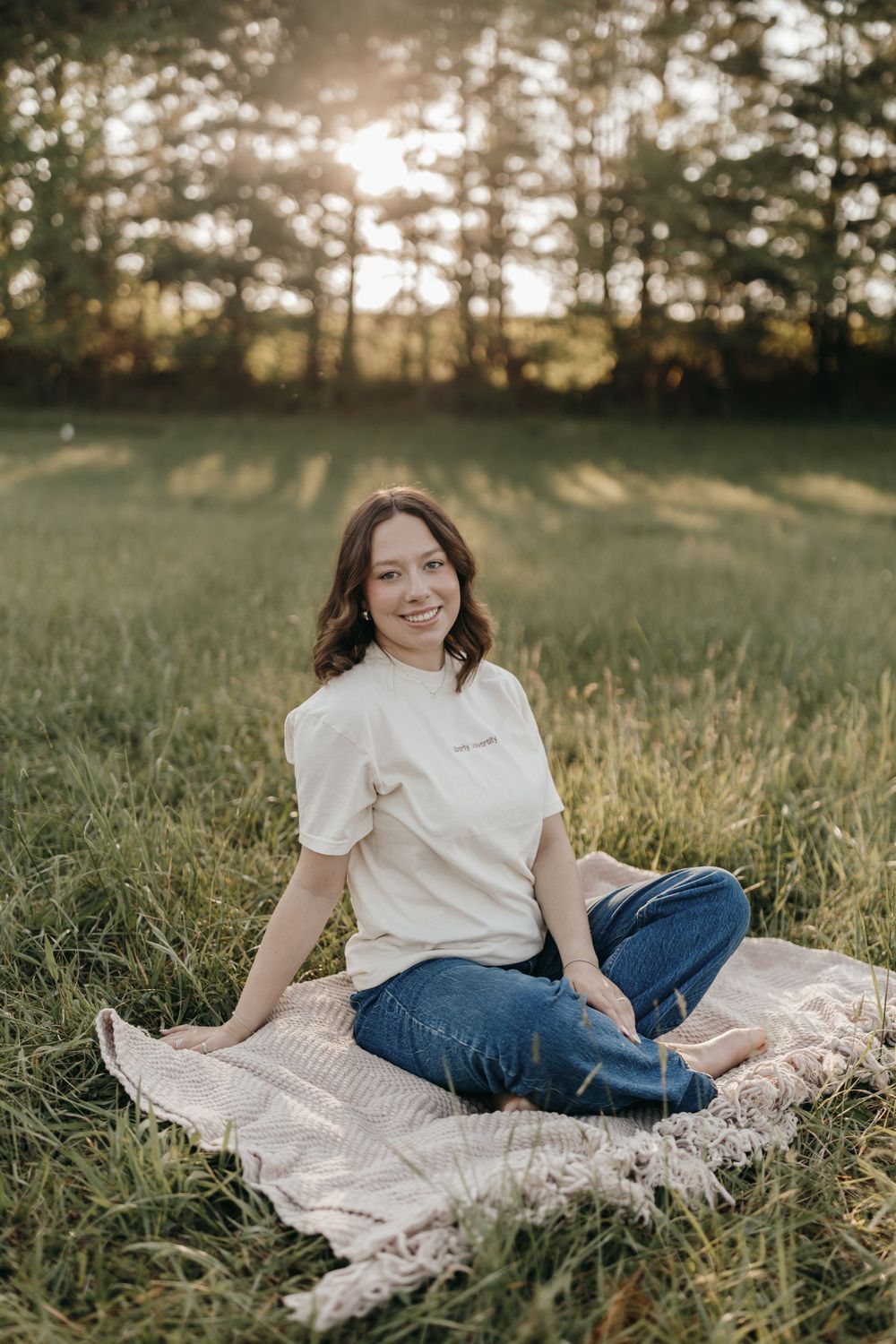 Outdoor portrait of someone sitting on a blanket in a grassy field during sunset. Virginia graduation/senior session.