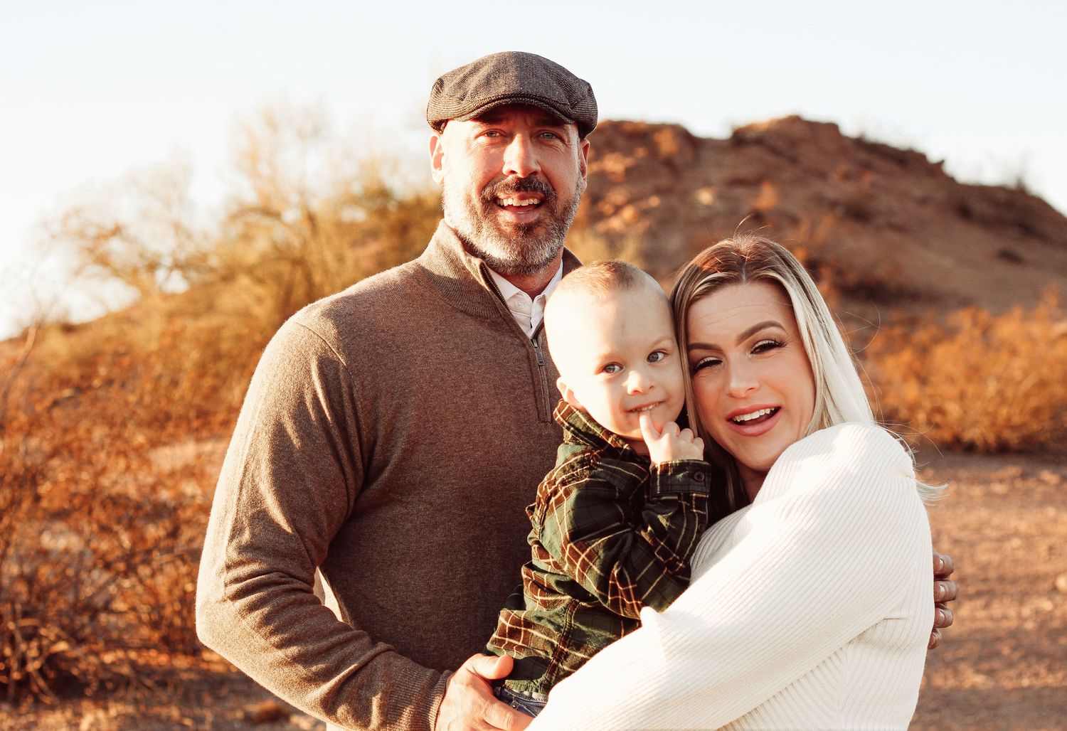 Family shares warm moment together against desert backdrop during sunset.