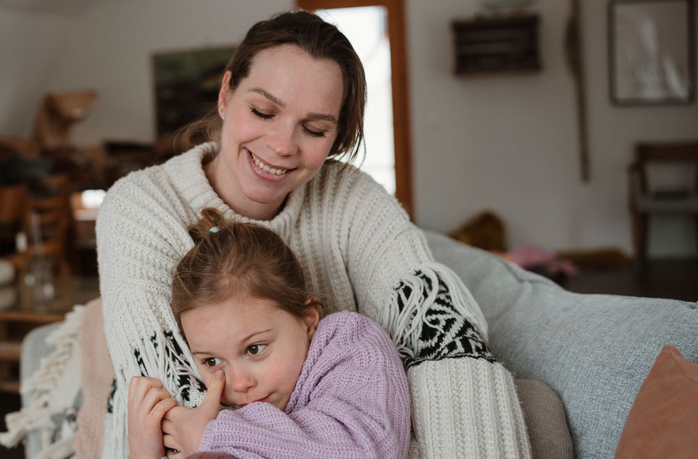 A tender moment of affection and comfort shared on a cozy couch with a soft pink teddy bear.