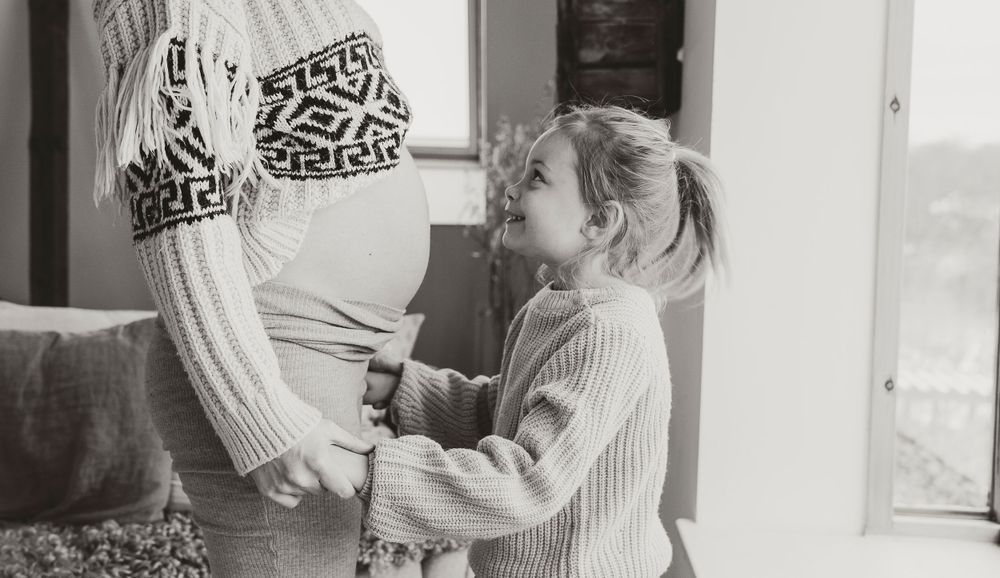 Sweet black and white moment between toddler and pregnant belly.