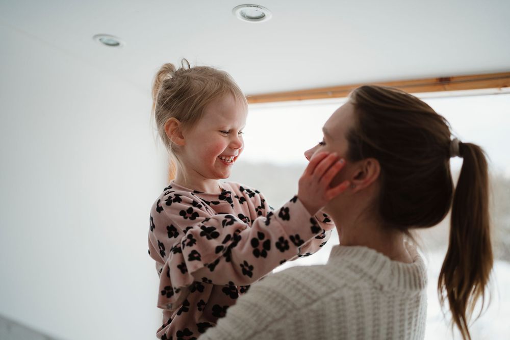 Candid moment of laughter and playful interaction between parent and child in a bright room.