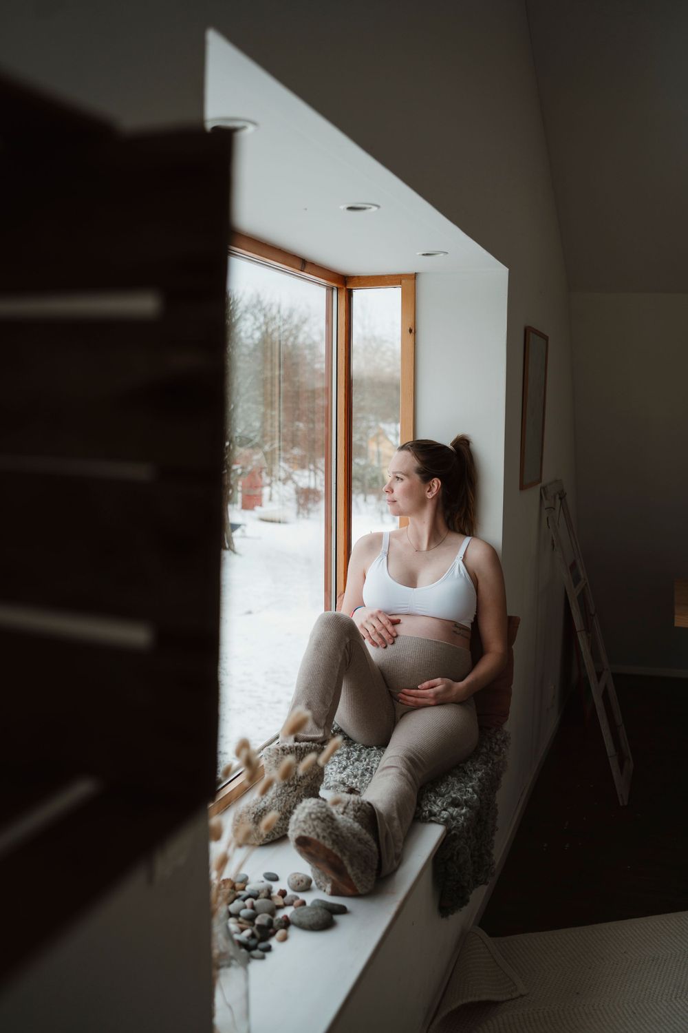 Expecting mother relaxing in cozy window nook during winter.