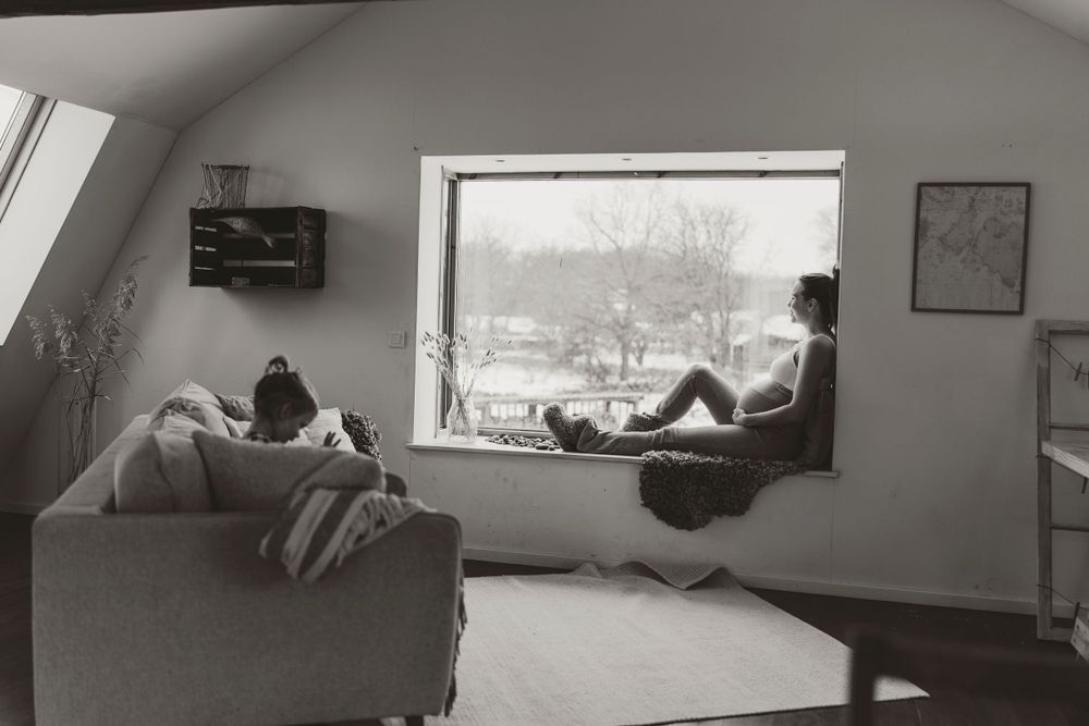Black and white photo of people relaxing in window seat with winter view.