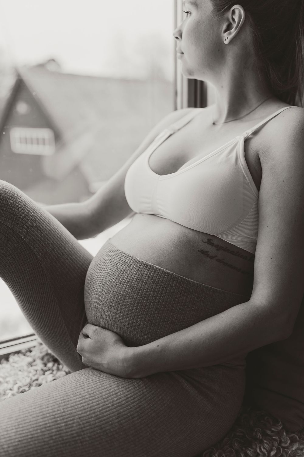 Intimate black and white maternity portrait by window light.