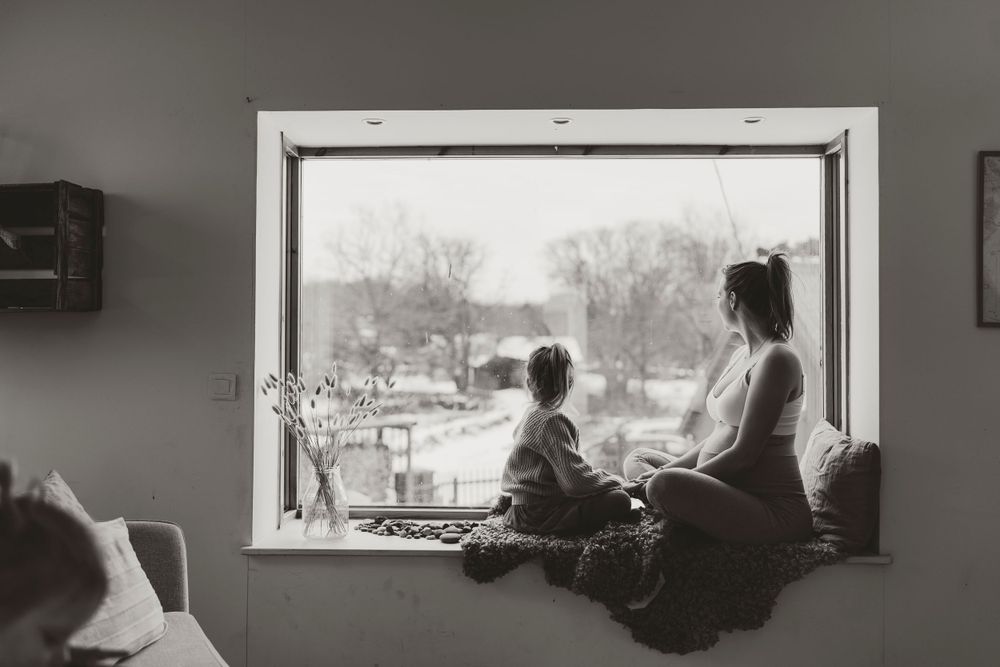 Monochrome image of window seat overlooking snowy landscape.