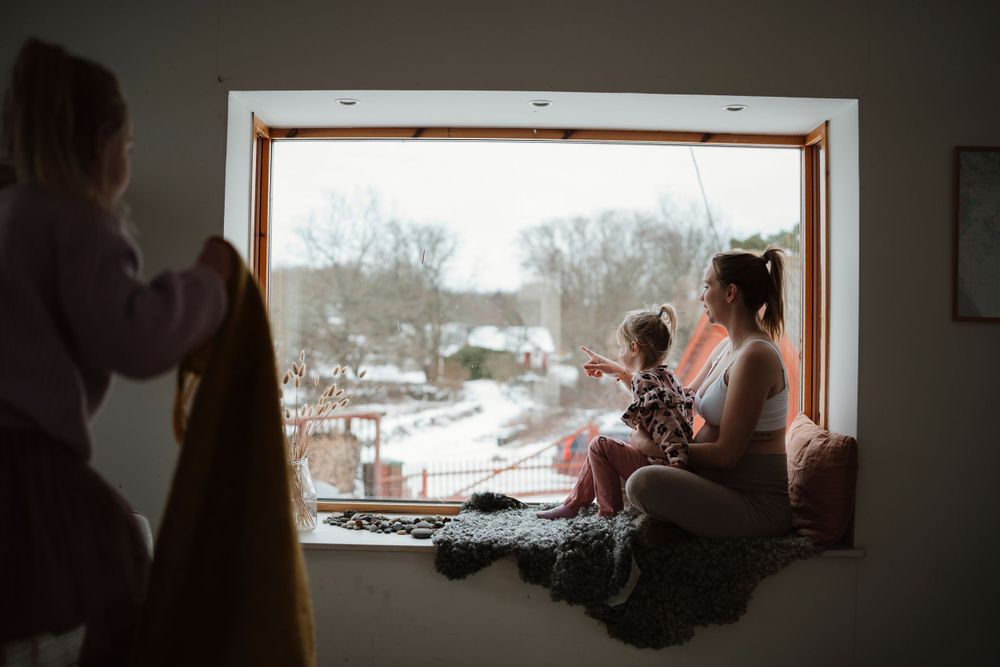 Cozy winter scene of family gathering by large picture window.