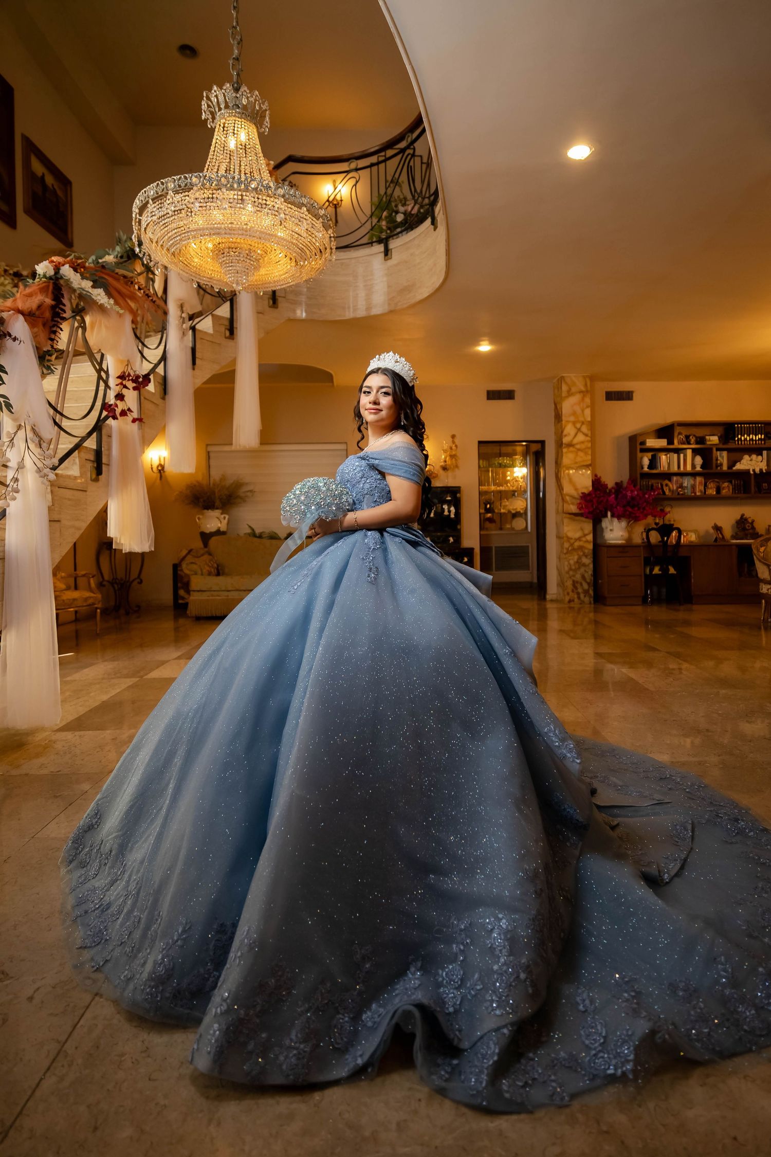 Royal blue quinceañera dress photographed under dramatic tree branches.
