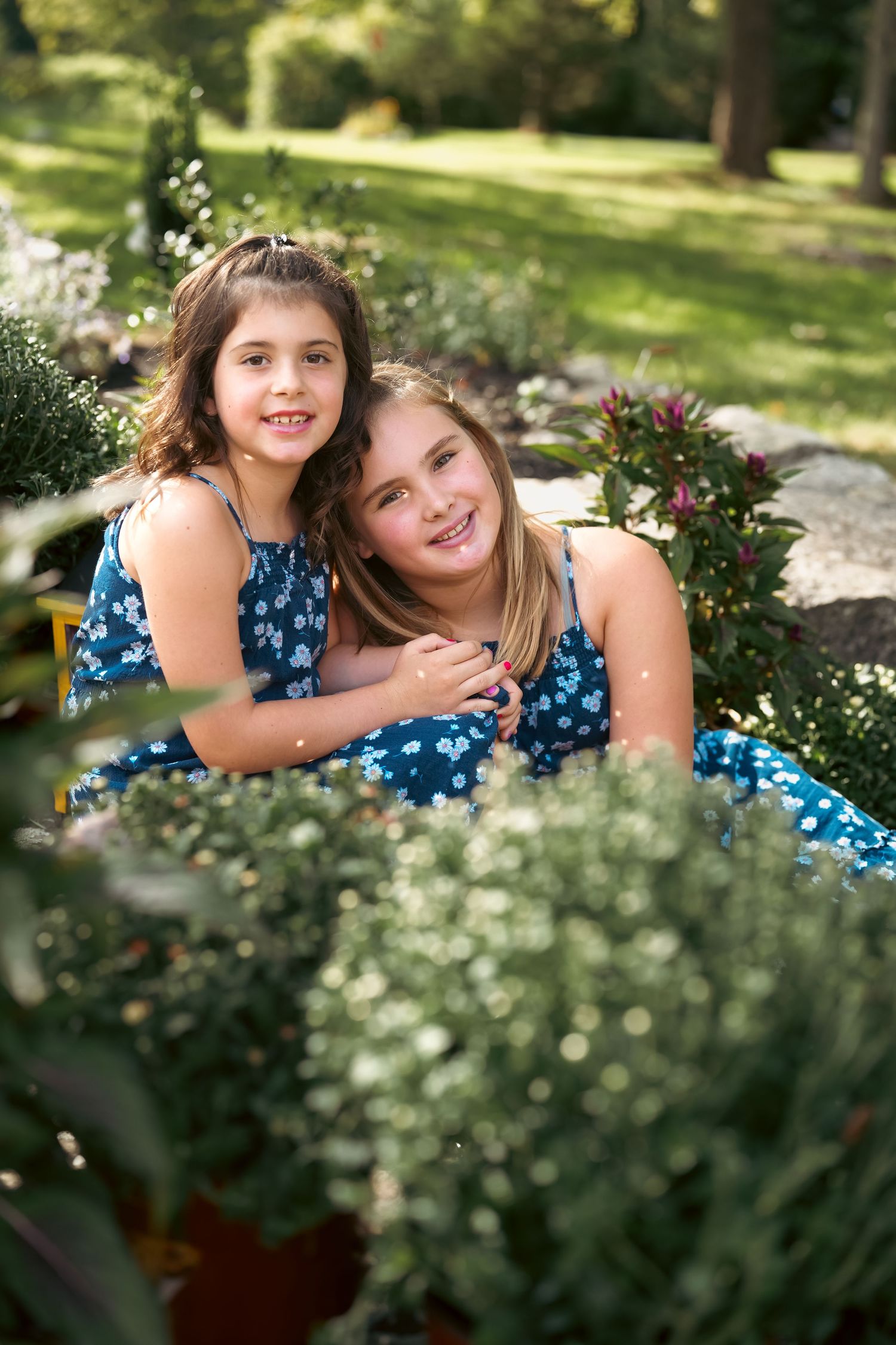 Candid outdoor portrait session among blooming flowers and garden foliage.