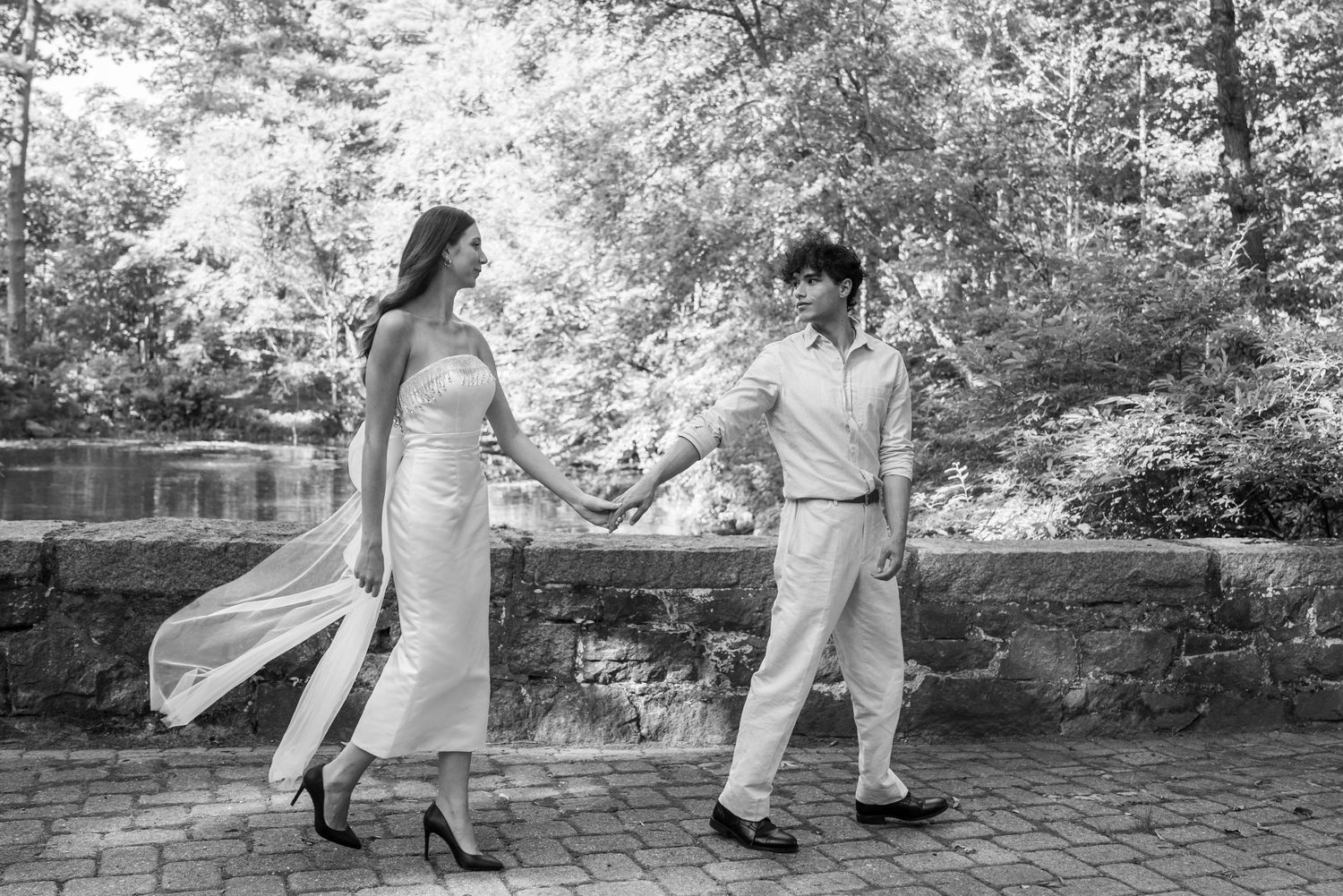 A couple dancing together on a brick patio with flowing dress and romantic movement in black and white.