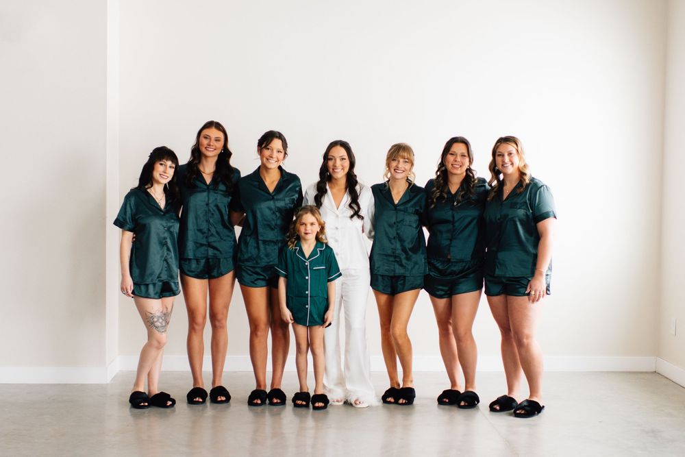 Group photo of wedding party in matching emerald green silk pajama sets.
