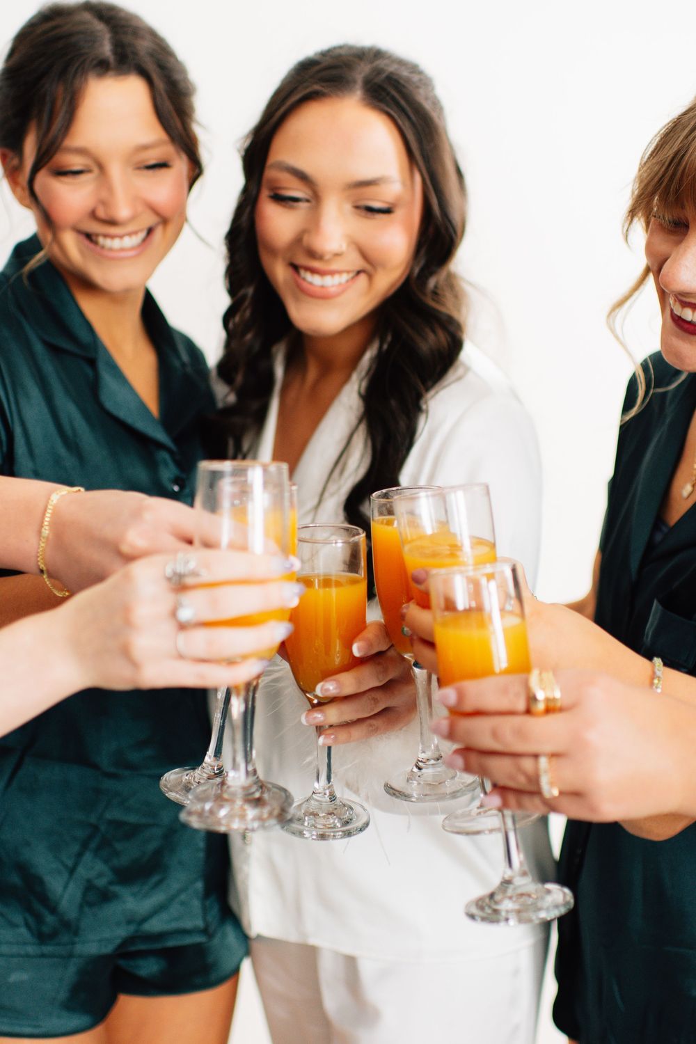 Friends in matching outfits toasting with mimosas during celebration.