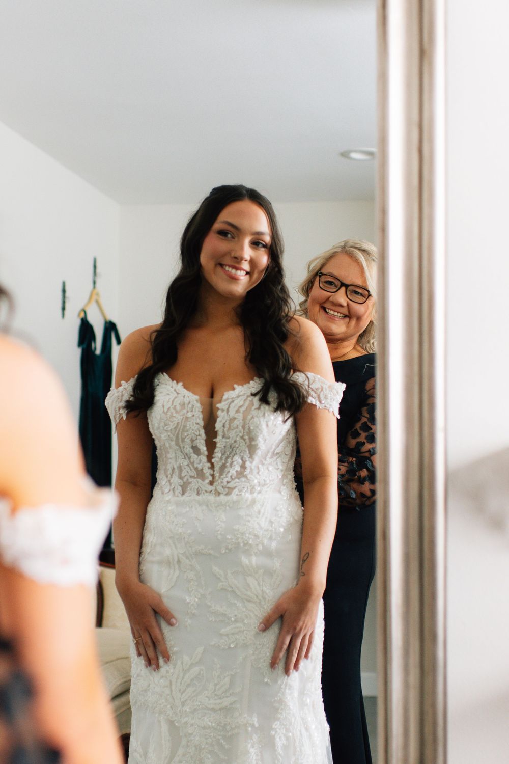 Joyful moment captured in mirror during wedding dress fitting.