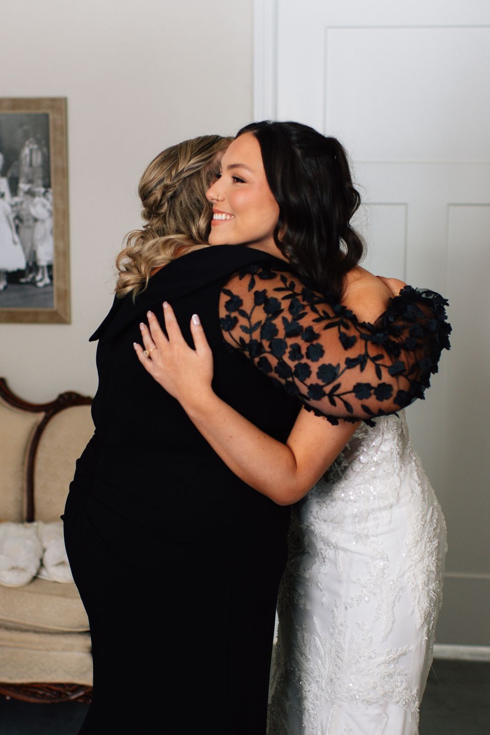Emotional wedding day first look moment showing joyful embrace between bride and loved one in black dress.
