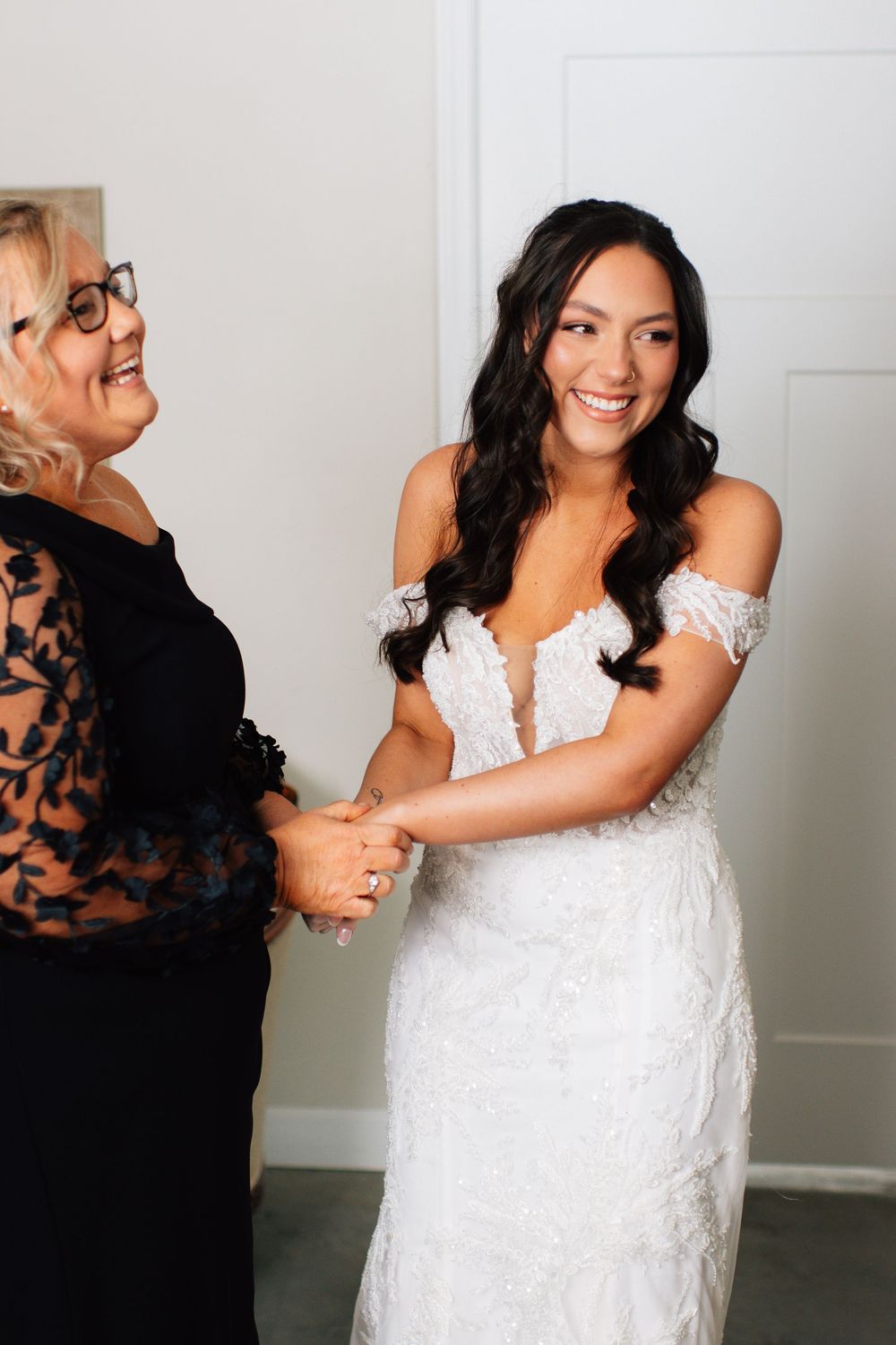 Candid sequence of heartfelt hugs and smiles between bride and wedding guest in black lace dress.
