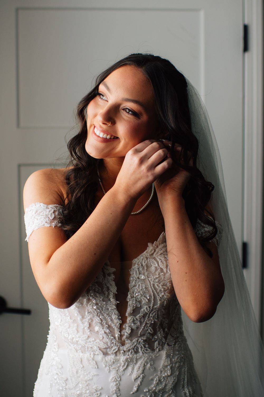 Bride in lace wedding dress laughing joyfully during candid portrait session.