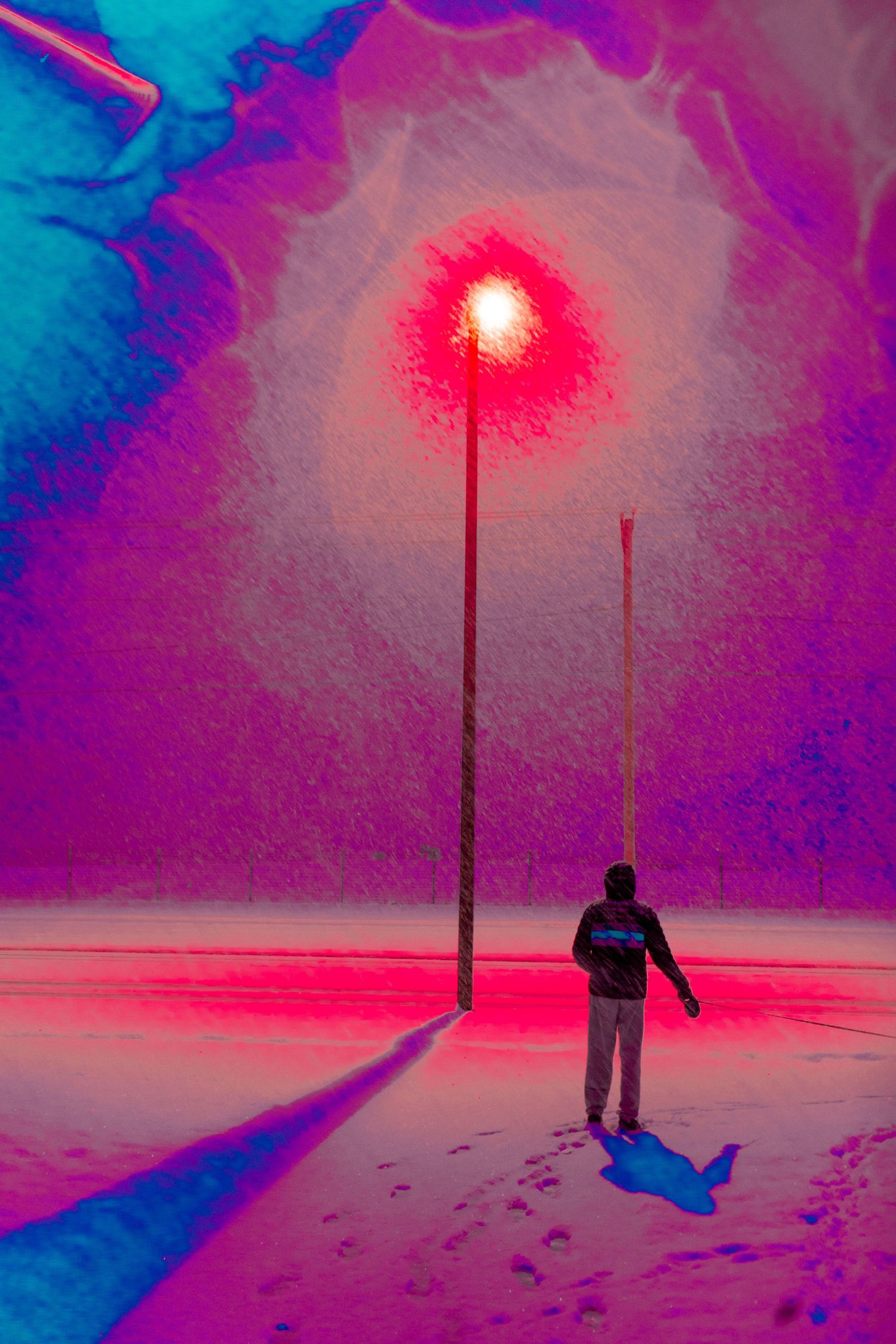 A silhouetted figure stands beneath red streetlights casting an ethereal glow on snowy ground during nighttime.