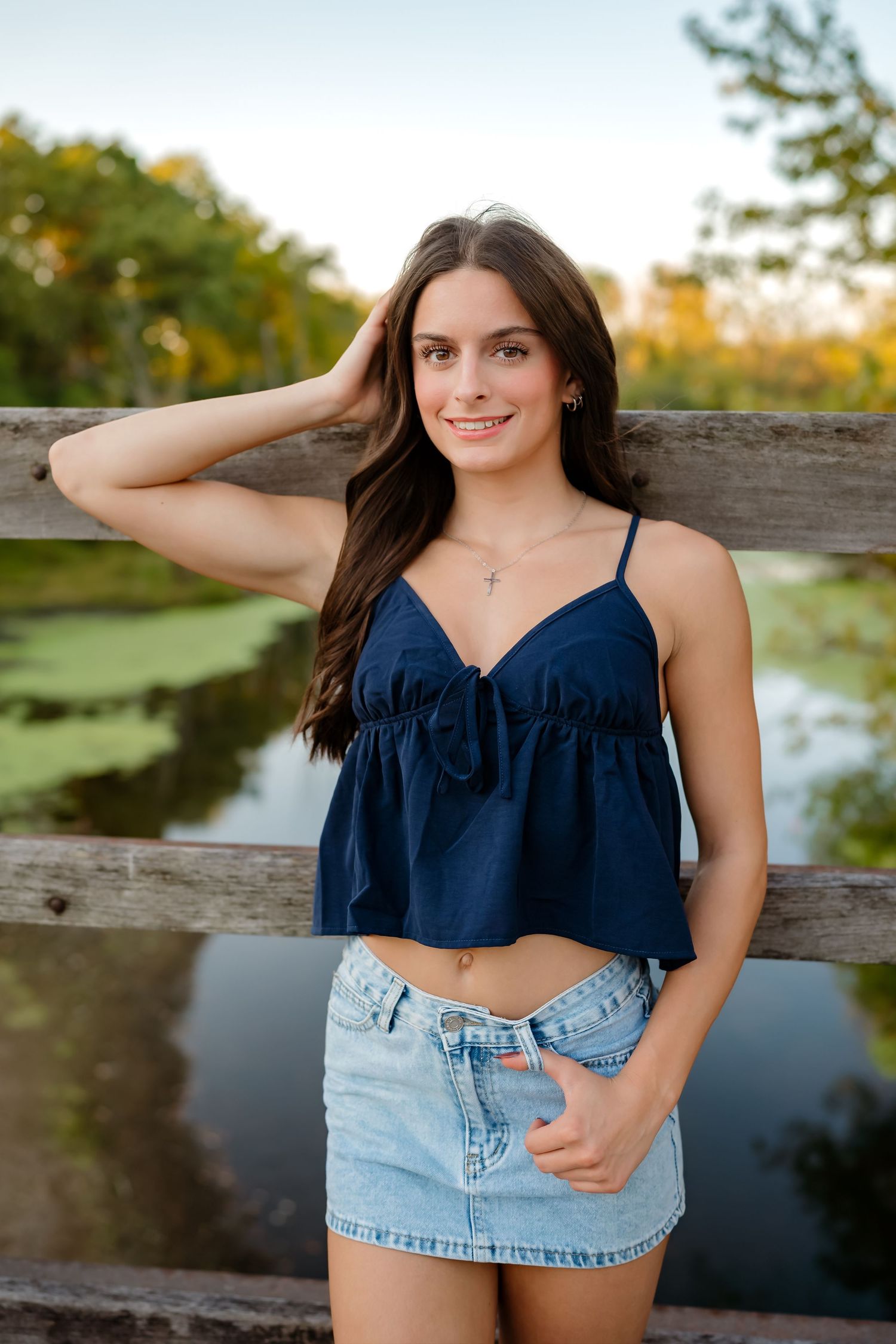 Summer portrait showing a navy crop top and denim skirt against a scenic lake backdrop at sunset.
