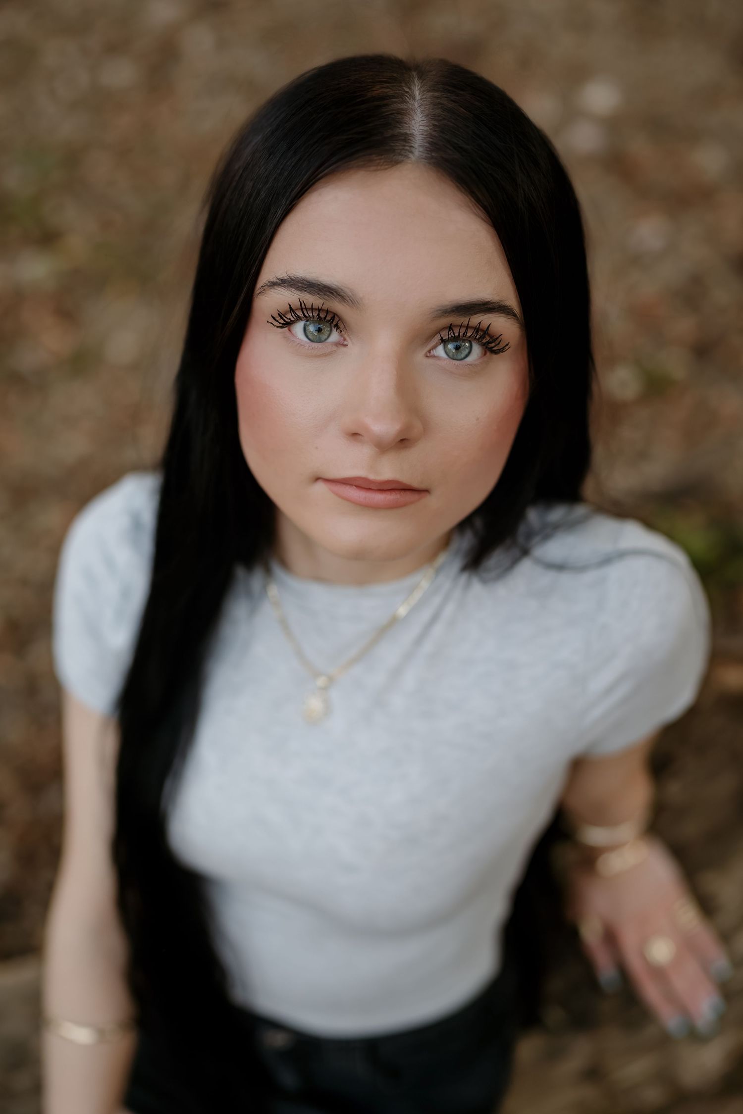 Close up portrait shot with dramatic lighting showing bright blue eyes and dark hair against a blurred background.