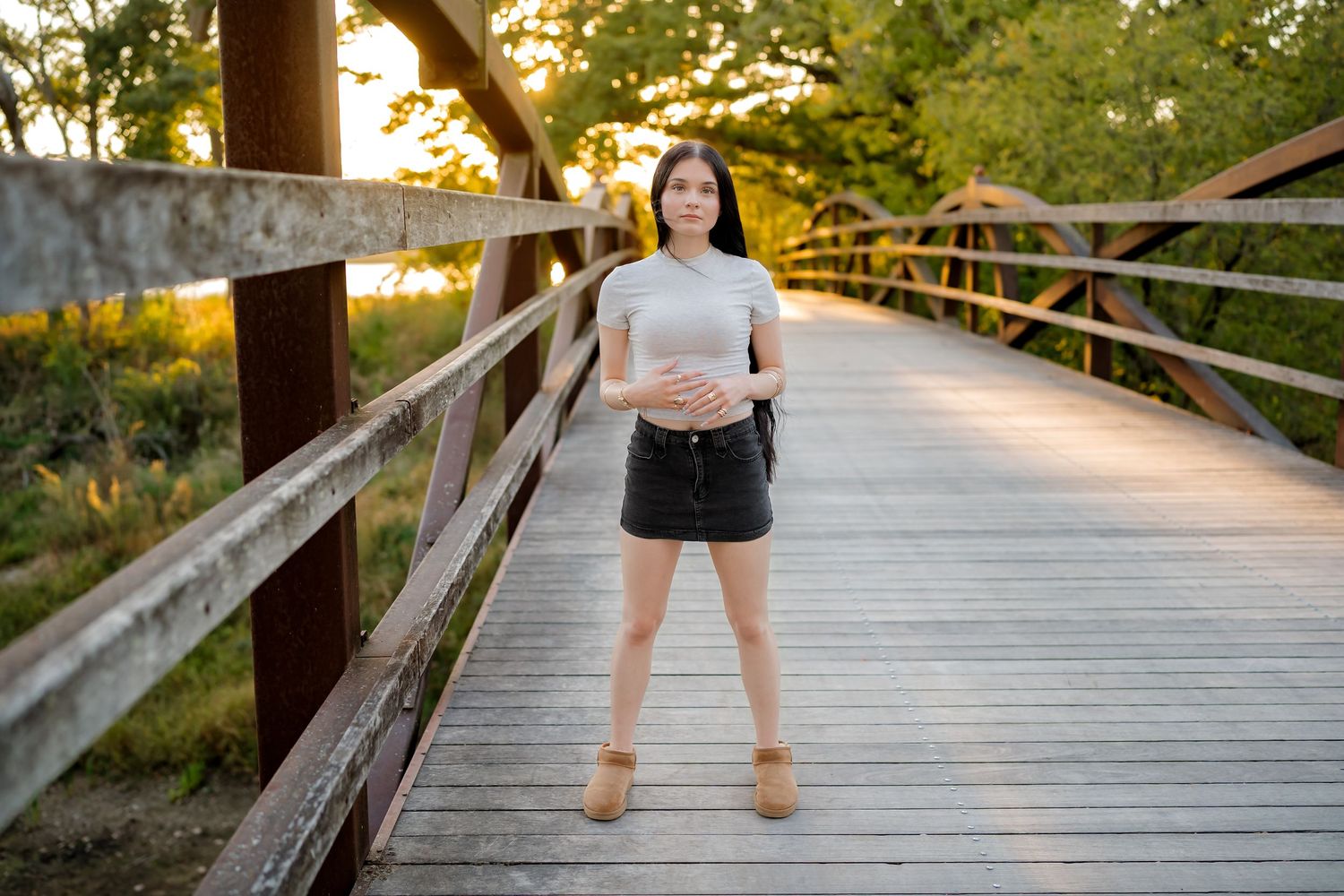 A wooden boardwalk path extends through lush greenery at sunset with golden light filtering through the trees.