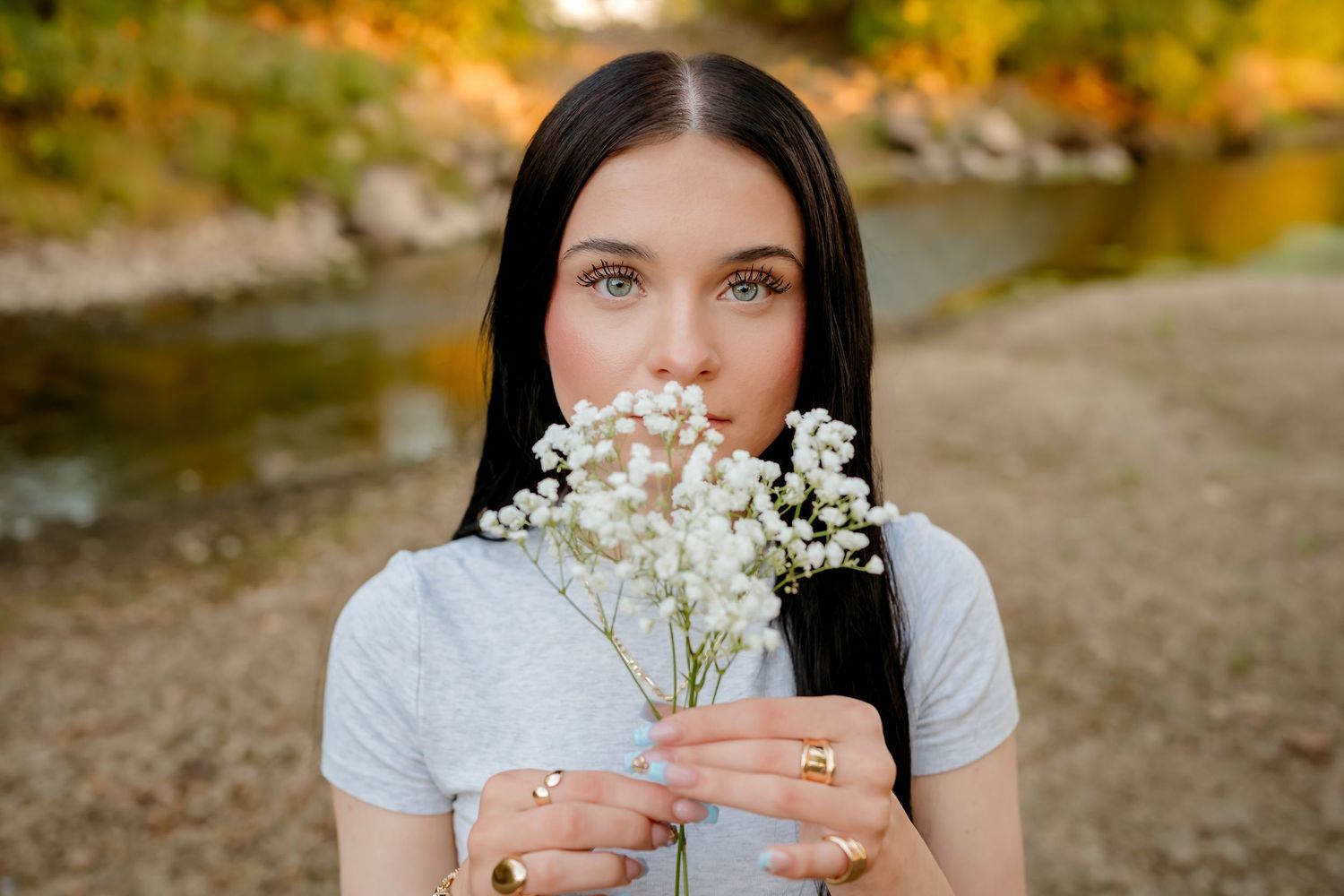 Someone holds delicate white baby's breath flowers against a natural outdoor background at golden hour.