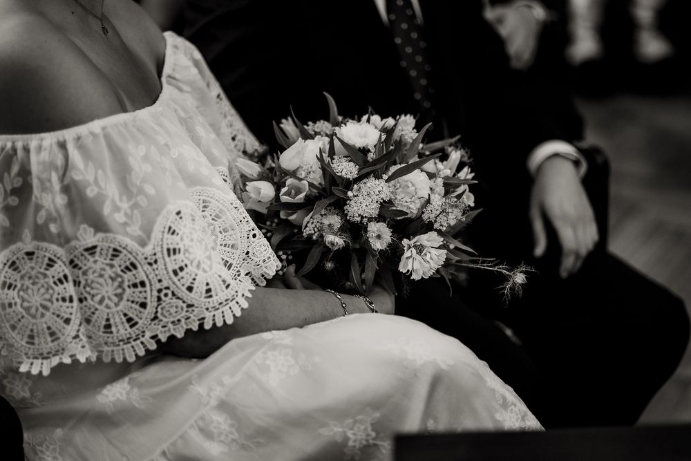 Black and white wedding detail photos showing lace, flowers, and delicate bridal accessories arranged in a collage.