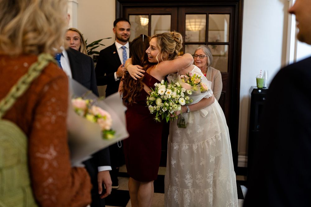 A wedding party gathers in a rustic barn venue with exposed wooden beams and warm lighting.