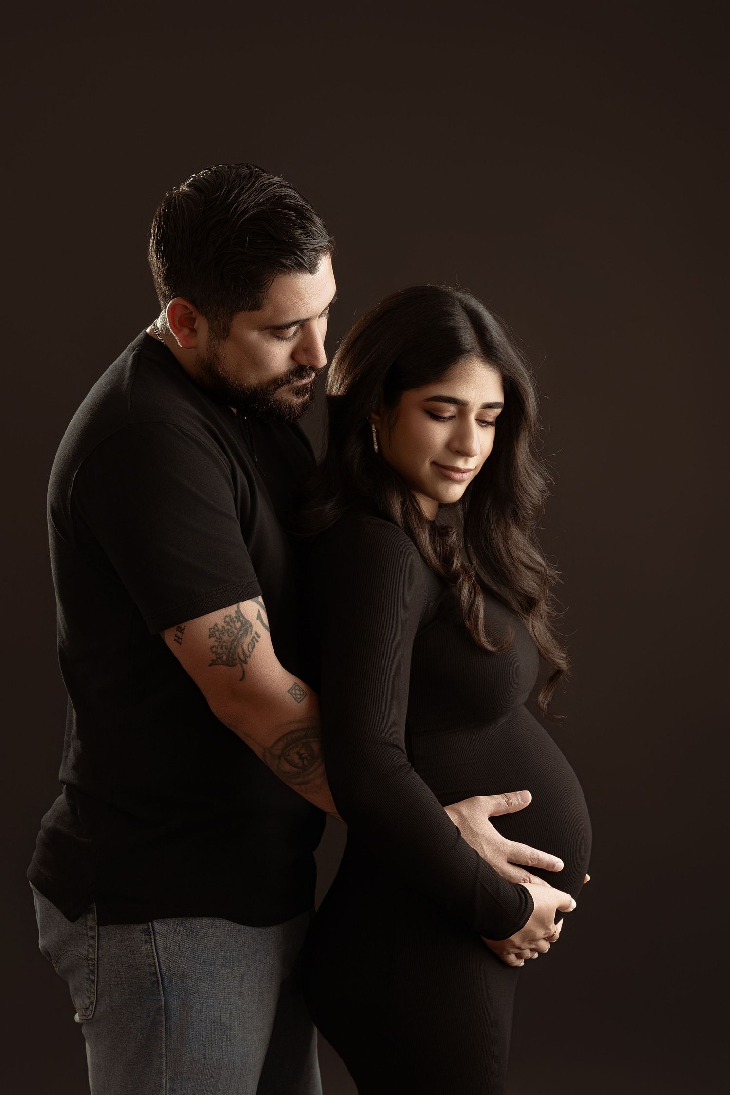 A romantic couple in black clothing poses intimately against a dark background in a series of connected photos. Paloma Schell
