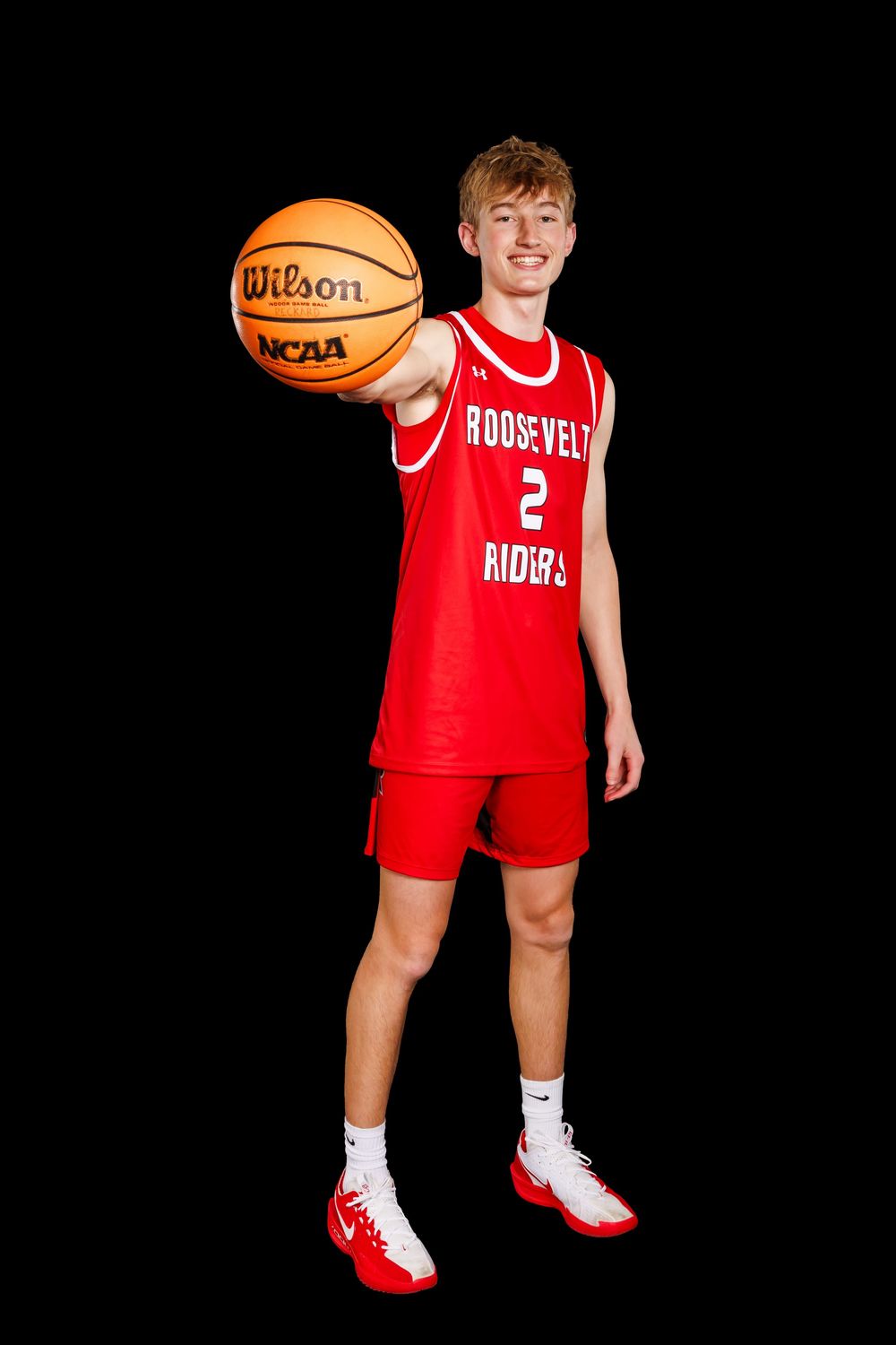 Basketball player in red Roosevelt Riders uniform number 2 poses with Wilson NCAA basketball against black background.