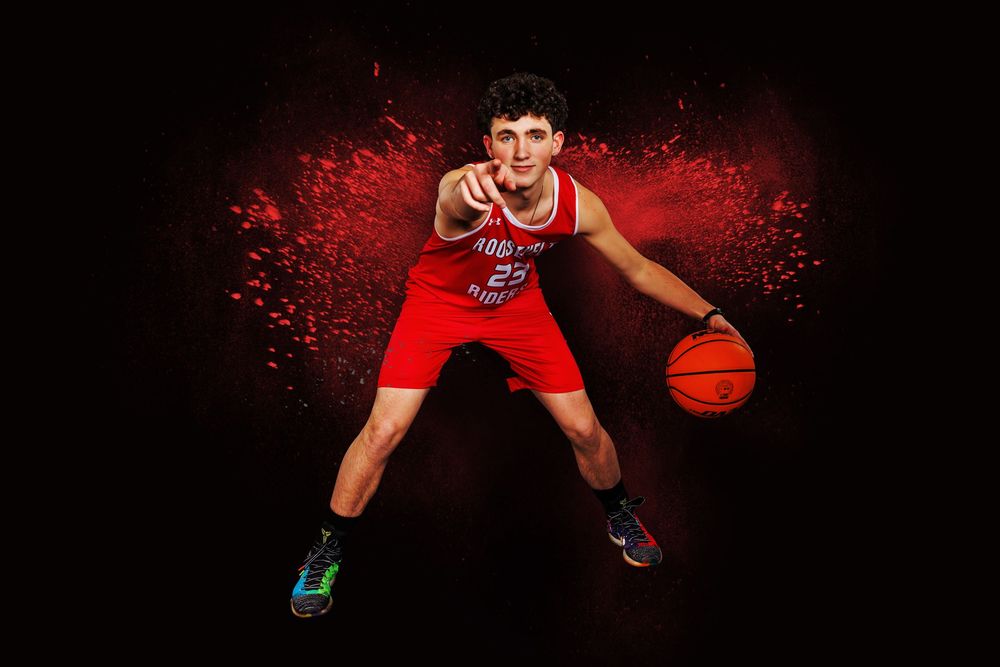 Basketball player poses in dramatic red lighting with ball and Roosevelt uniform.
