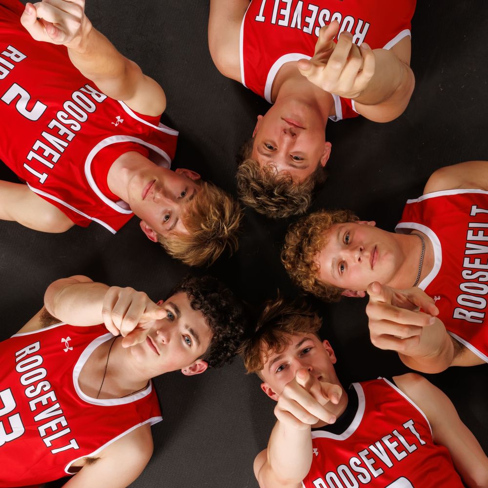 Basketball team members in red jerseys lying on the floor in a creative circular formation for a photo shoot.