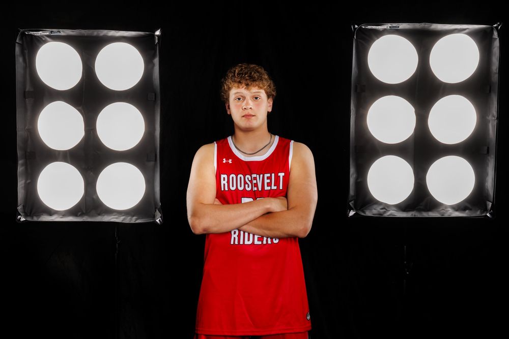 Basketball player in red Roosevelt uniform poses with dramatic studio lighting.