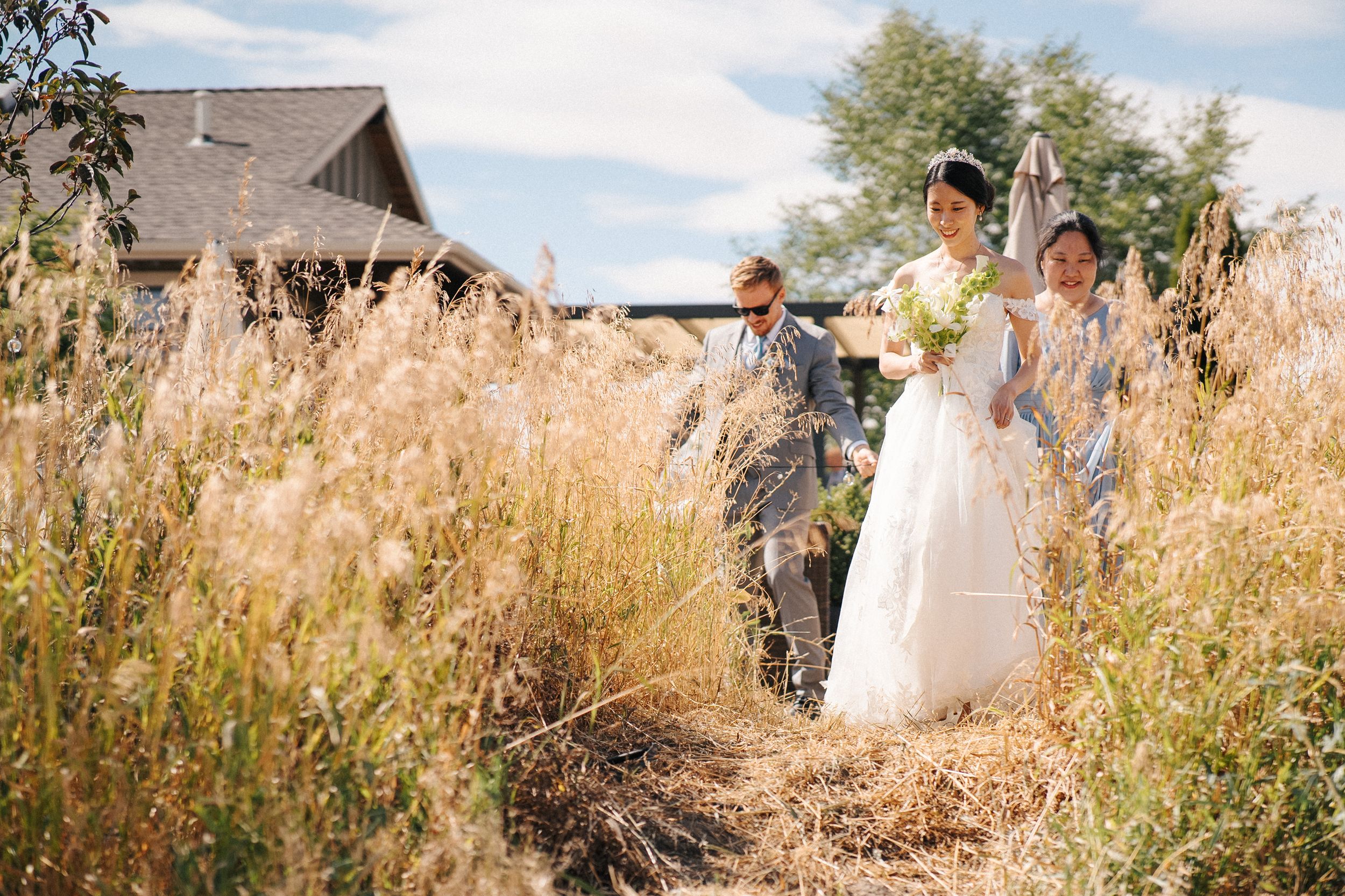 Wedding couple poses together in a golden wheat field at sunset with mountains in the background.
