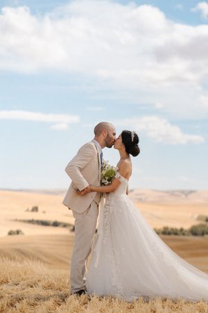 Romantic wedding portraits captured in a golden wheat field against a dramatic rural landscape.