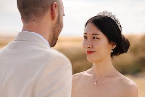 Close up profile view of a couple in wedding attire standing in a sunlit field.