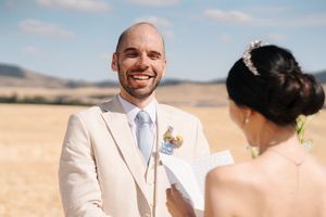Wedding couple sharing joyful moment in sun-drenched wheat field.