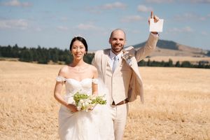 Wedding celebration in a rustic wheat field with scenic mountain views.