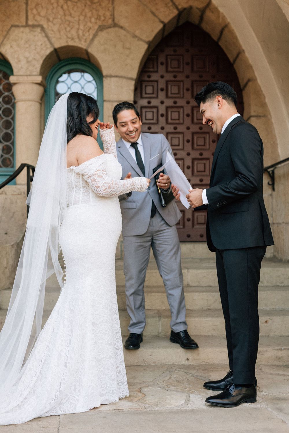 A micro wedding taking place on the stone steps at the Santa Barbara Courthouse while the couple laughs