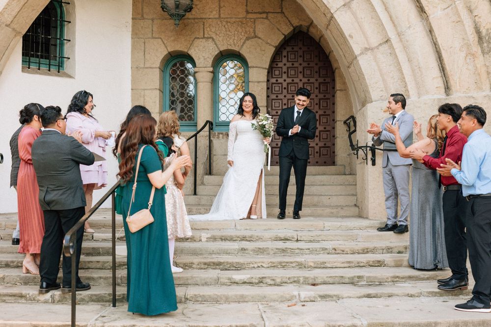 A bride and groom smile at their micro wedding guests as the guests cheer at the Santa Barbara Courthouse after the couple elopes