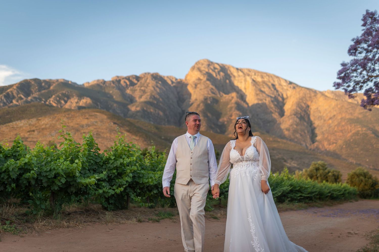 A couple poses for wedding photos at sunset against a stunning mountain backdrop in Utah.