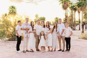 Large family portrait in Papago Park with the golden hour glow hitting the palm trees behind them in Papago Park.