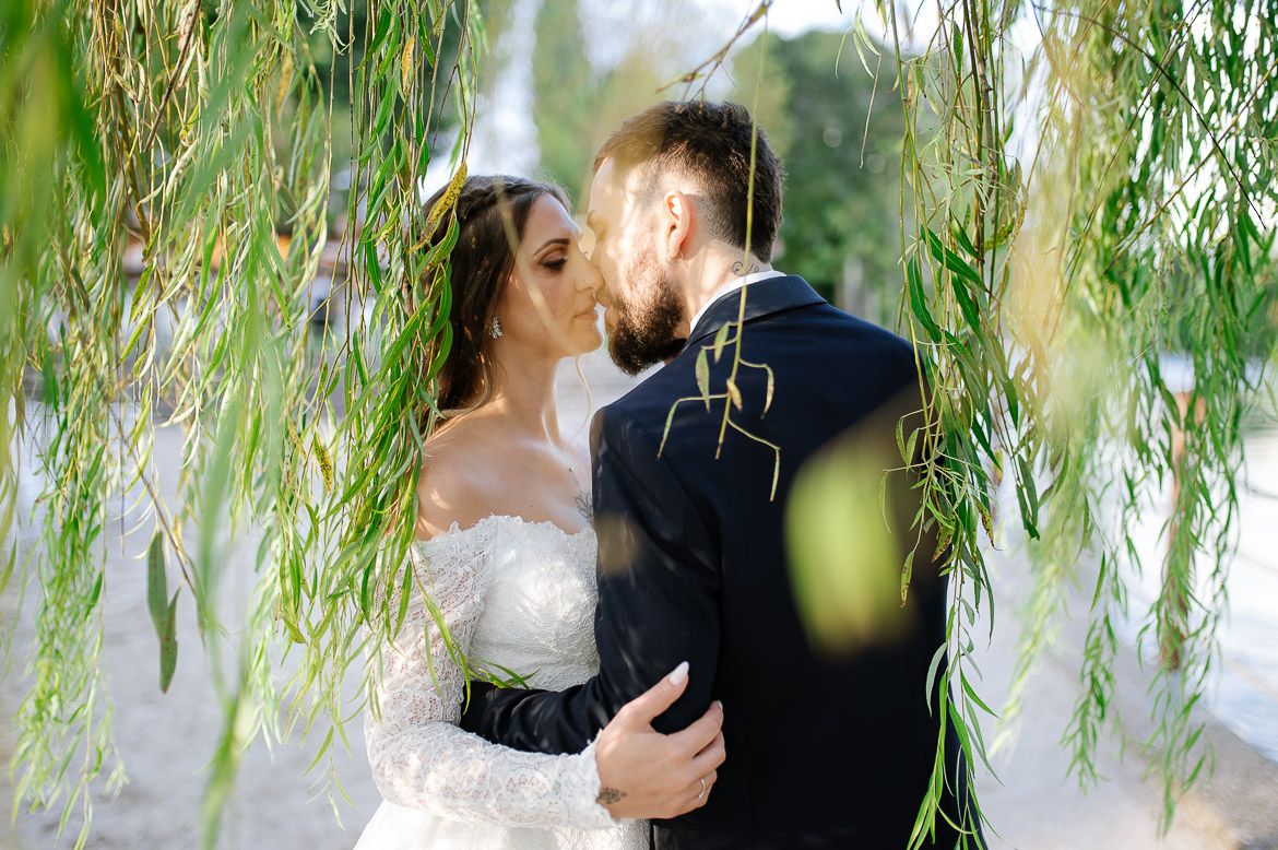 A couple shares a romantic moment under a weeping willow tree during their wedding photo session.