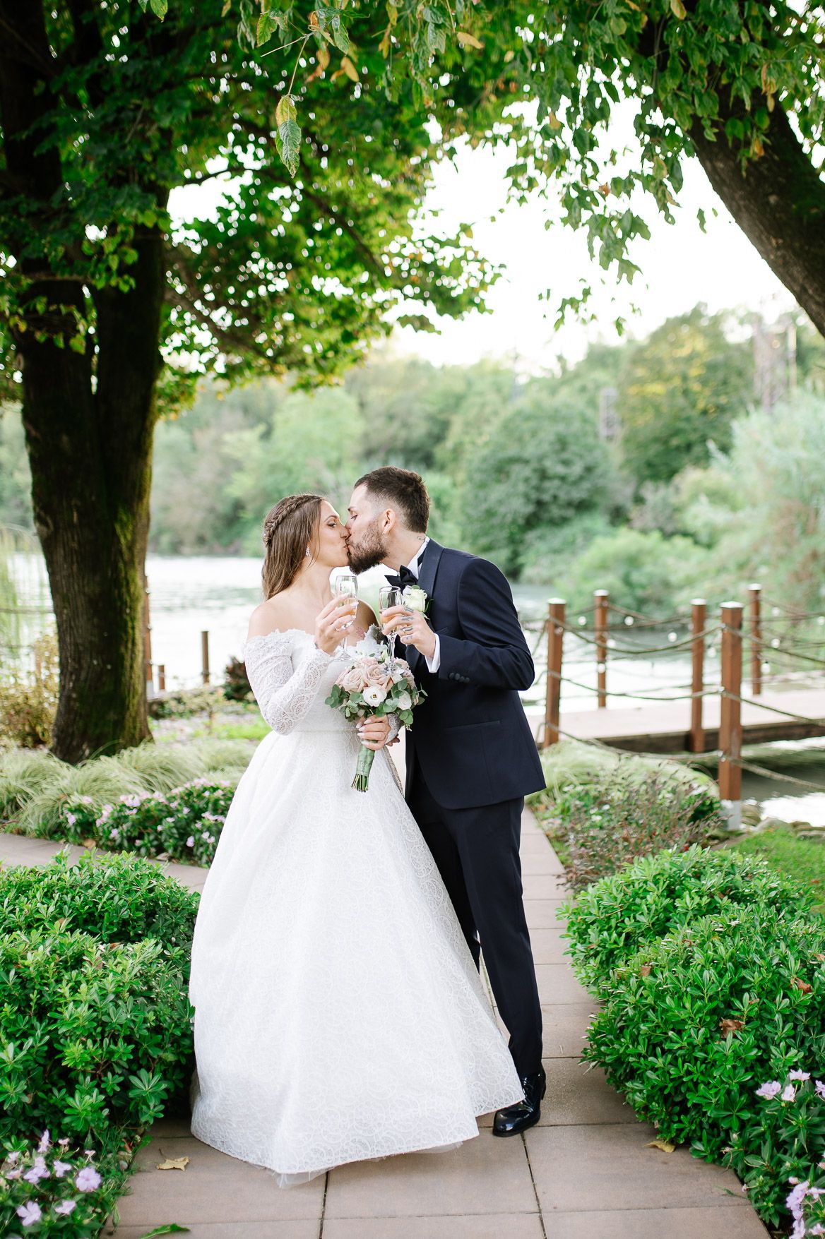 Romantic wedding couple shares intimate moments on a garden pathway surrounded by lush greenery.