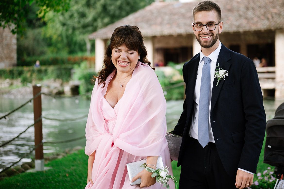 Wedding party members walk together outdoors in formal attire with pink accents and floral details.